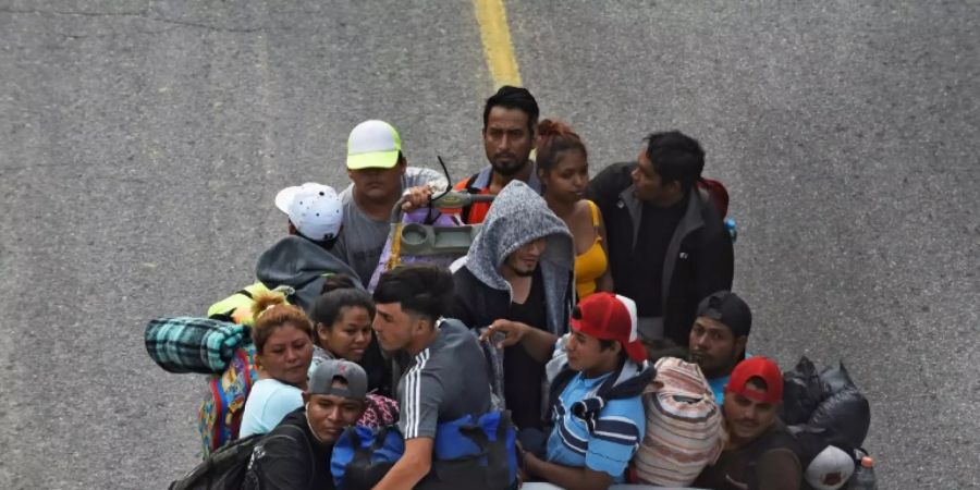 Migrants heading in a caravan to the US, ride on the back of a truck in El Arenal, Mexico, on November 18, 2021