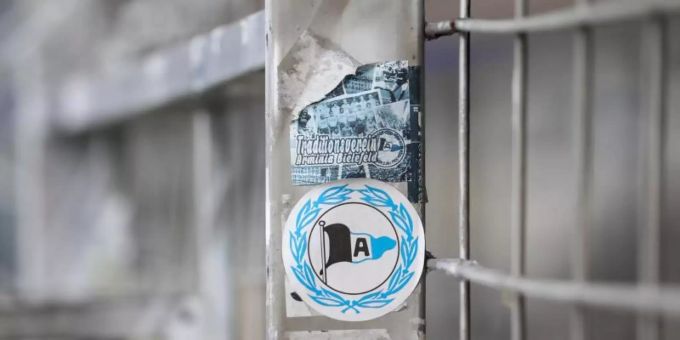 Ein Aufkleber mit dem Logo von Arminia Bielefeld klebt auf einem Zaun. Foto: Friso Gentsch/dpa Ein Aufkleber mit dem Logo von Arminia Bielefeld klebt auf einem Zaun. Foto: Friso Gentsch/dpa