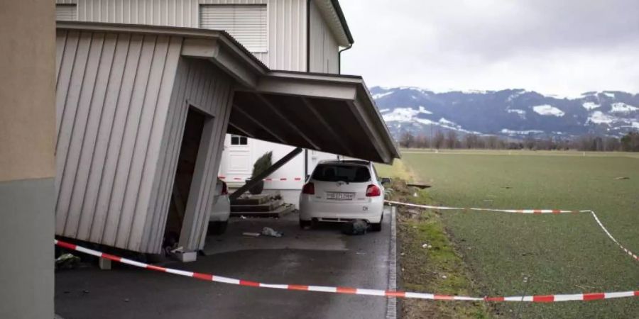 Das Dach eines beschädigten Hauses ragt nach Sturm «Uwe» auf ein davor geparktes Auto. Foto: Gian Ehrenzeller