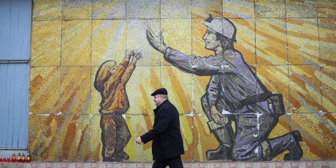 Ein Mann geht an einem Mosaikdenkmal für den Bergbau vorbei.