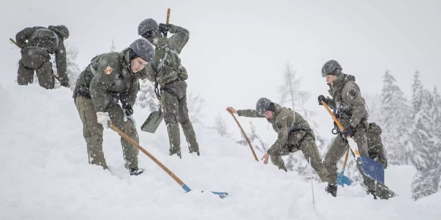 Bundesheer-Soldaten schippen Schnee von dem Dach eines Hauses.