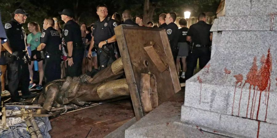 Polizisten bewachen die umgestürzte Statue eines Konföderierten, Silent Sam genannt. Rund 250 Demonstranten haben auf einem Universitätscampus im US-Bundesstaat North Carolina ein Denkmal für Soldaten der ehemaligen Südstaaten Amerikas gestürzt.