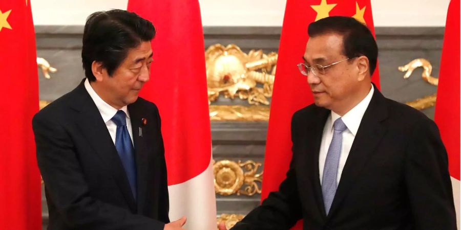 Li Keqiang, Premierminister von China, und Shinzo Abe, Premierminister von Japan, gehen aufeinander zu.