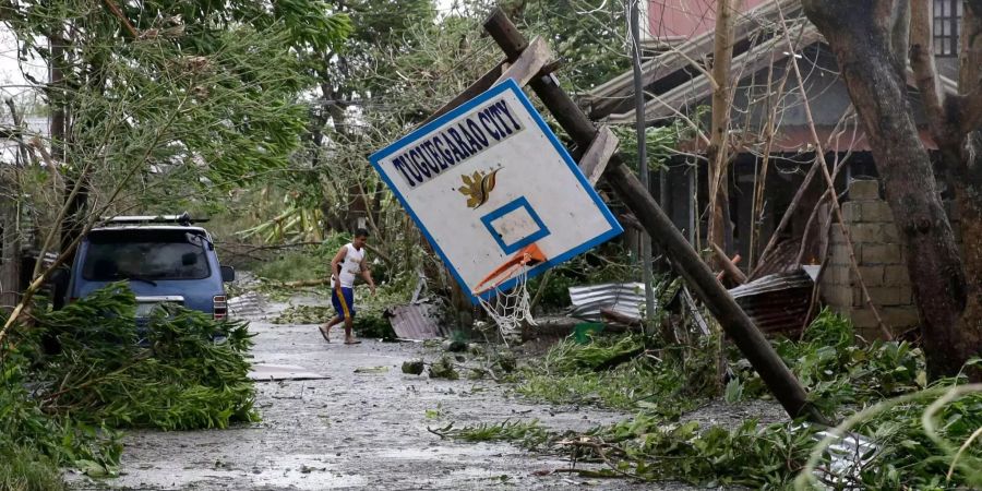 Ein Anwohner geht in der Nähe eines umgestürzten Basketballkorbs.