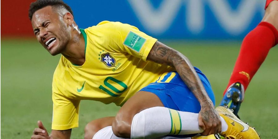 Neymar hält sich das Schienbein mit schmerzverzerrterm Gesicht.