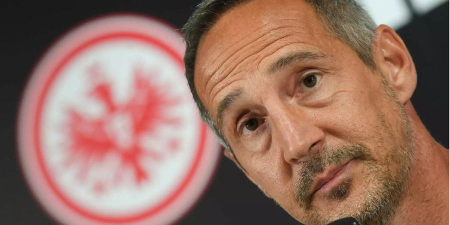 Eintracht Frankfurts Cheftrainer Adi Hütter sitzt während einer Pressekonferenz vor dem Vereinswappen.