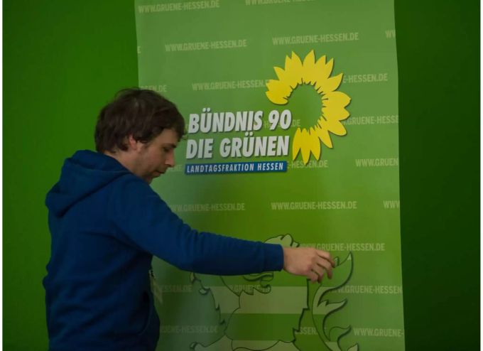 Ein Mitarbeiter der hessischen Grünen schiebt einen Aussteller von Bündnis 90/ Die Grünen zurecht. Bei der Landtagswahl in Hessen haben CDU und SPD starke Verluste hinnehmen müssen. Nach dem vorläufigen amtlichen Endergebnis können aber Schwarz-Grün mit hauchdünner Mehrheit weiter regieren. Nach der Landtagswahl in Hessen - Grüne
