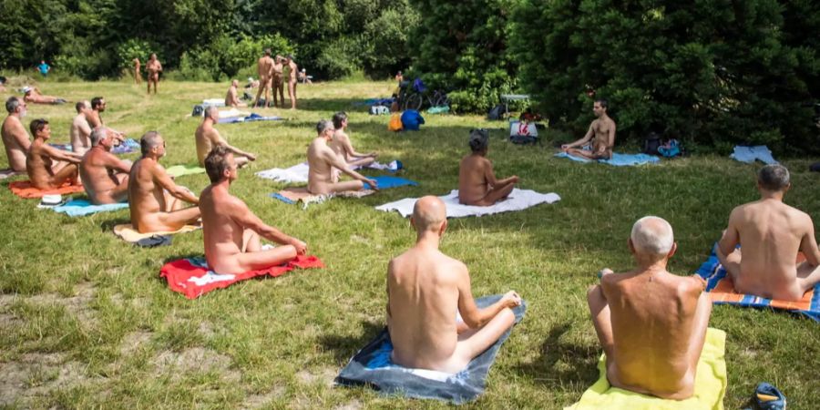 Eine Gruppe nackter Menschen bei einer Yoga-Lektion im Grünen. FKK ist aus der Mode gekommen, die FKK-Vereine leiden an Überalterung.