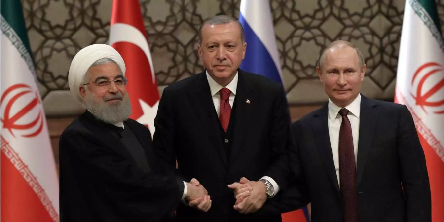 Der iranische Präsident Hassan Rouhani (l), der russische Präsident Vladimir Putin (r), und der türkische Präsident Recep Tayyip Erdogan halten sich an den Händen nach einer gemeinsamen Pressekonferenz.