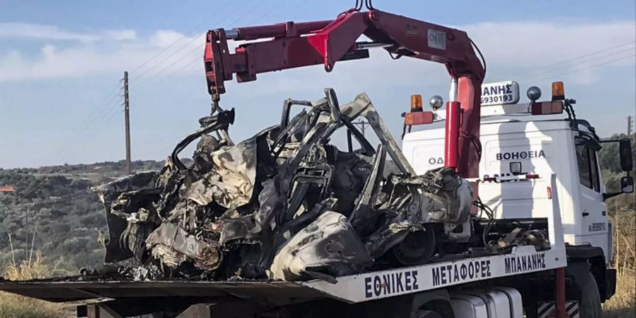 Die Überreste eines verbrannten Fahrzeugs werden auf einen Lastwagen geladen.