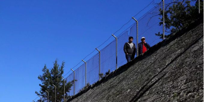 Zwei Personen gehen einem Grenzzaun auf Zypern entlang. Zwei Personen gehen einem Grenzzaun auf Zypern entlang.