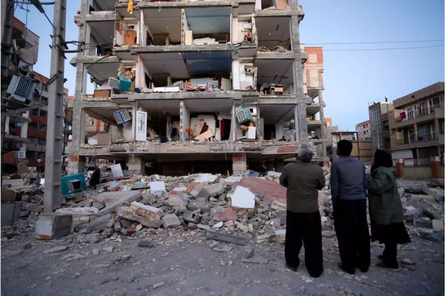 Erdbebenopfer stehen vor einem zerstörten Gebäude in Sarpol-E-Zahab (Iran).