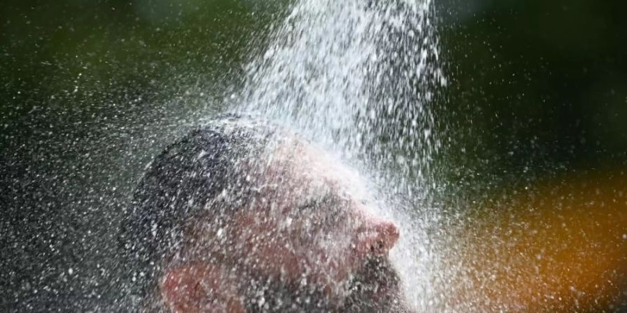 Ein Mann kühlt sich im Freibad unter einer Dusche ab. Foto: Patrick Seeger/dpa