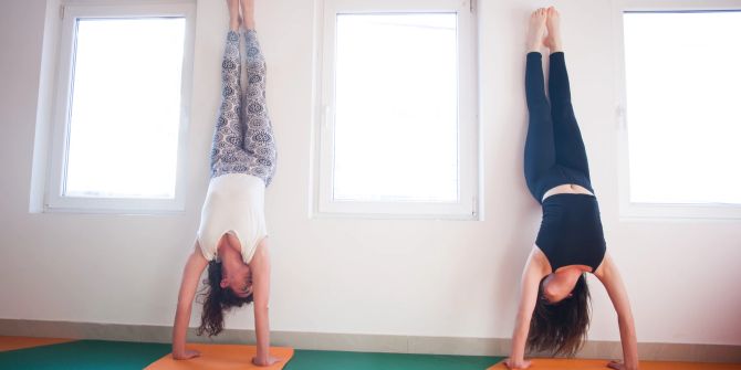 Frauen im Handstand gegen eine Wand.