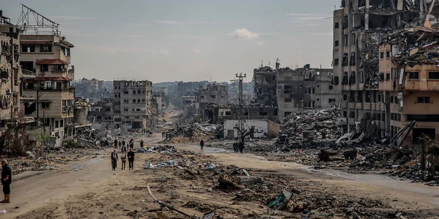 Palästinenser gehen durch die Überreste des zerstörten Scheich-Radwan-Viertels in Gaza-Stadt. Foto: Omar Ishaq/dpa