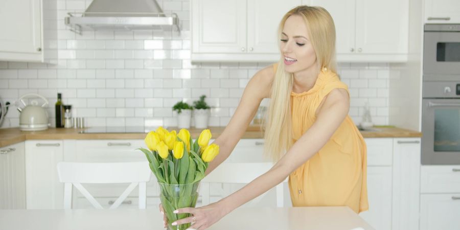 Frau stellt Vase mit Tulpen auf den Tisch