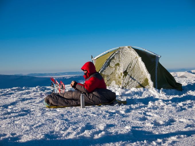 Gerade wenn man Zelten möchte, sollte man fürs Camping im Winter etwas aufrüsten. Mann zeltet im Winter