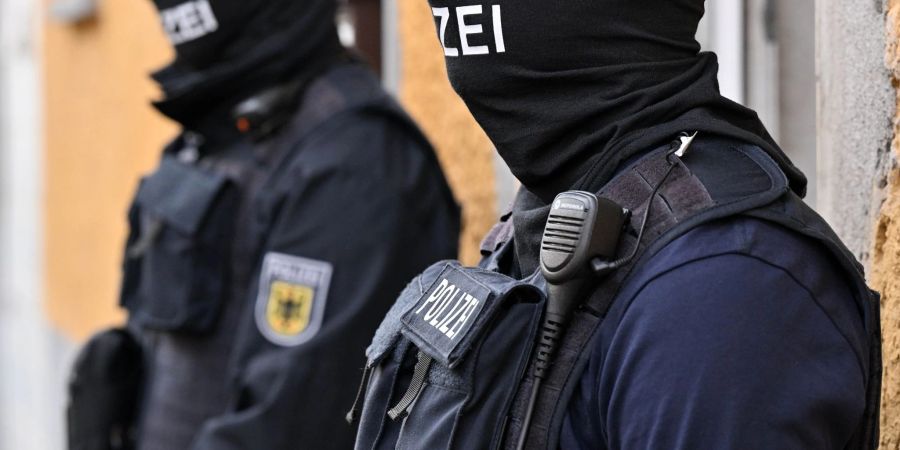 Bundespolizisten stehen vor einem Hauseingang. (Archivbild)