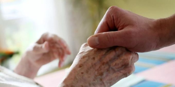 Pfleger hält Hand einer Heimbewohnerin Pfleger hält Hand einer Heimbewohnerin