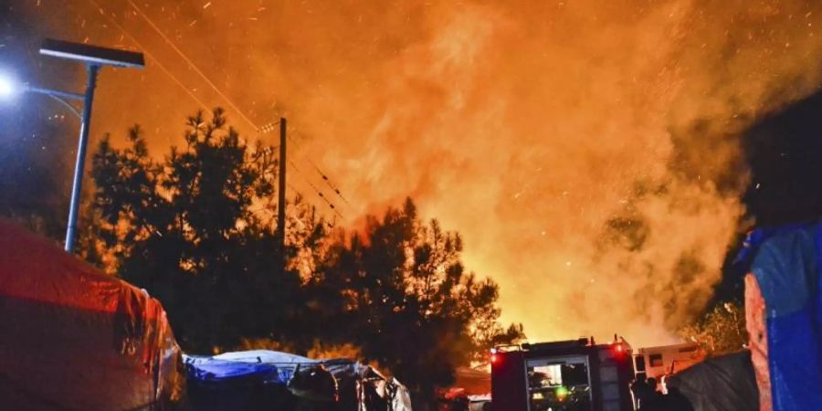 Feuerwehrleute kämpfen gegen den Brand in dem überfüllten Migrantenlager. Foto: Michael Svarnias/AP/dpa