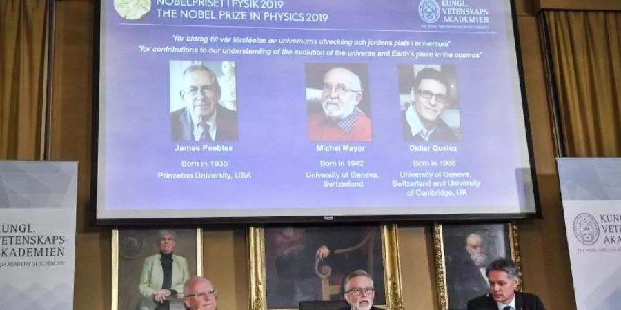 Der Nobelpreis für Physik geht in diesem Jahr an James Peebles (l-r auf der Leinwand), Michel Mayor und Didier Queloz. Foto: Claudio Bresciani/TT NEWS AGENCY/AP/dpa