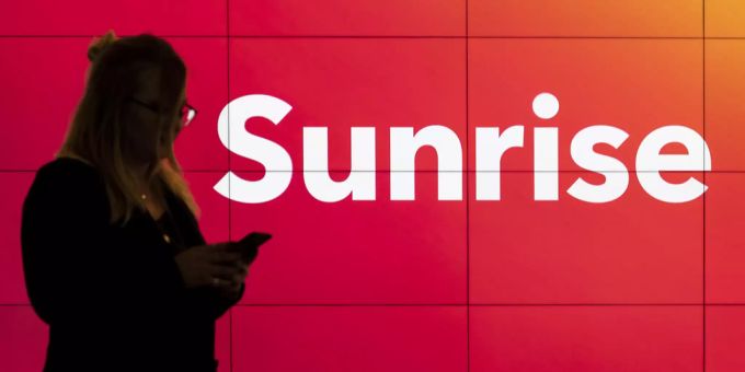 Eine Kundin steht vor dem Schriftzug vor einem Sunrise-Shop. sunrise communications
