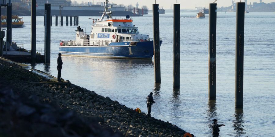 Polizeitaucher und Polizeibeamte bei der Suche nach dem Jungen in der Elbe.