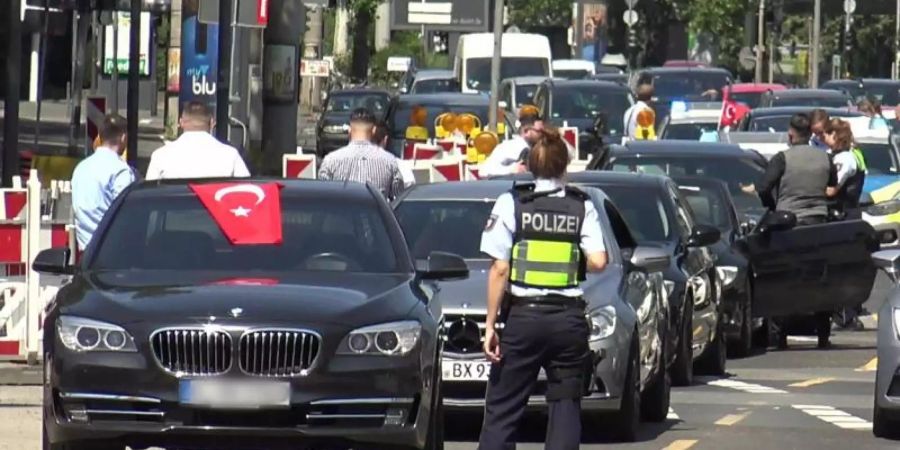 Eine Polizistin steht vor den Fahrzeugen eines türkischen Hochzeutskorsos. Foto: Thomas Kraus/dpa