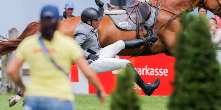 Der Reiter Philipp Weishaupt fällt von seinem Pferd Che Fantastica herab. Foto: Rolf Vennenbernd/Archivbild