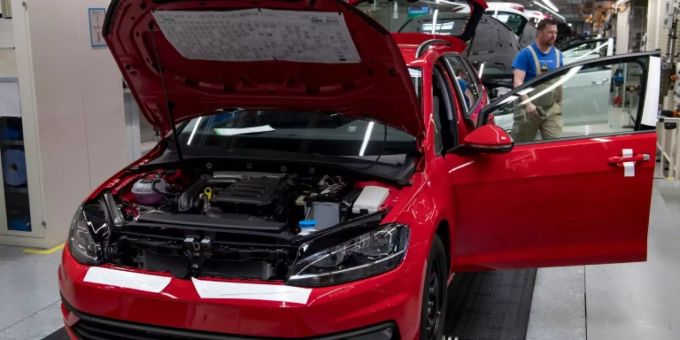 VW-Mitarbeiter montieren einen Golf. vw