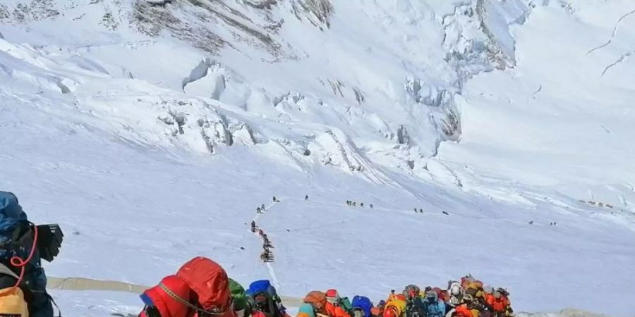 In einer langer Schlange klettern Bergsteiger auf einem Pfad knapp unterhalb von Lager vier. Foto: Rizza Alee/AP/dpa