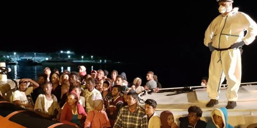 Flüchtlinge bereiten sich darauf vor, bei ihrer Ankunft im Hafen von Lampedusa aus einem Beiboot zu steigen (Archiv). Foto: Elio Desiderio/ANSA/dpa