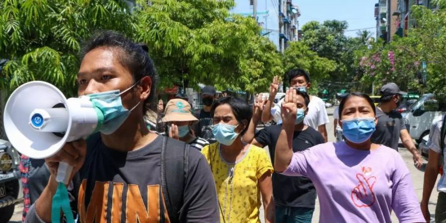 Menschen zeigen bei einer Demonstration in Yangon den Drei-Finger-Gruss als Zeichen des Widerstands. Foto: --/AP/dpa