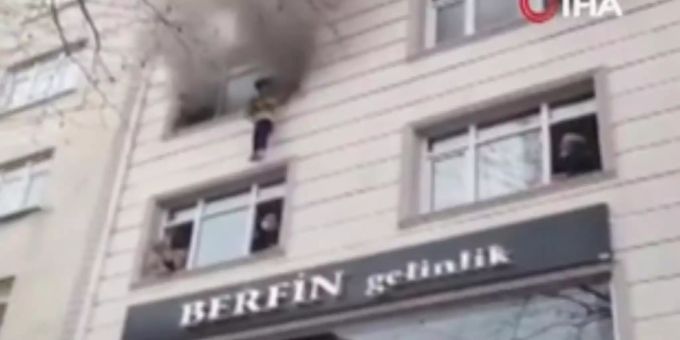 25.02.2021, Türkei, Istanbul: Auf diesem von IHA zur Verfügung gestellten Videostandbild wird eines von vier Kindern aus einem Wohnungsfenster auf Umstehende fallen gelassen, nachdem ein Feuer ausgebrochen ist. Eine Frau hat Kinder aus dem dritten Stock eines brennenden Hauses geworfen, um diese zu retten. Alle Kinder blieben unverletzt. Frau wirft Kinder aus brennendem Haus in Istanbul