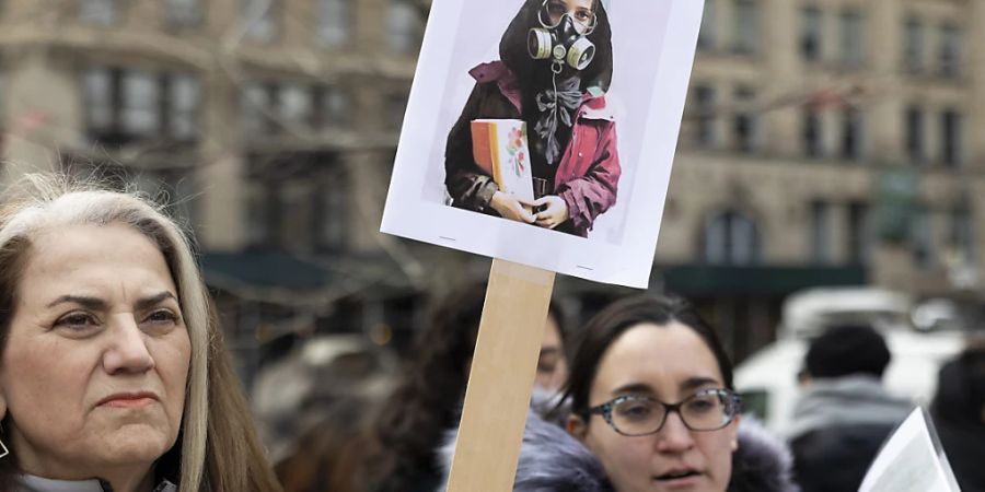 ARCHIV - Eine Frau in New York hält ein Schild mit dem Bild eines Mädchens, das ein Buch hält und eine Gasmaske trägt. Foto: Gina M Randazzo/ZUMA Press Wire/dpa
