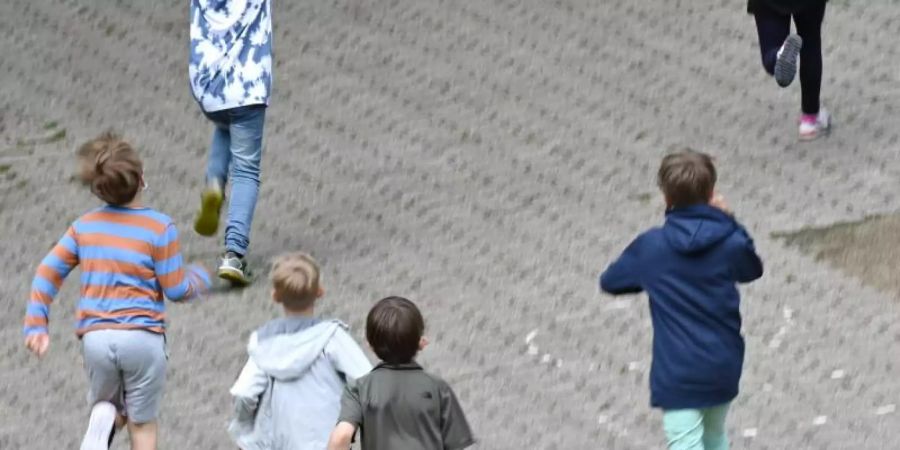Fröhlich rennen Schüler der Robert-Schumann-Grundschule in der grossen Pause auf den Schulhof. Foto: Arne Dedert/dpa