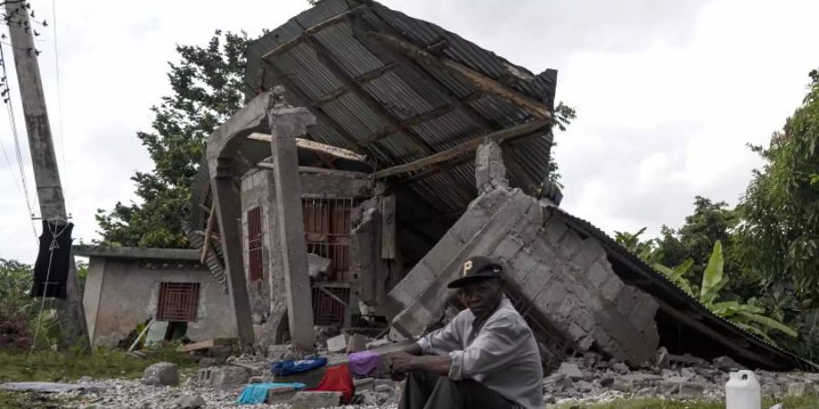Ein Mann sitzt vor einem zerstörten Haus in Haiti. Foto: David de la Paz/XinHua/dpa