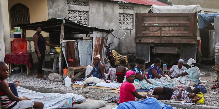 Einheimische, die die Nacht in Schlafsäcken im Freien verbracht haben, wachen am Tag nach einem Erdbeben auf. Das Erdbeben der Stärke 7,2 hat Haiti am 14.08.2021 erschüttert. Foto: Joseph Odelyn/AP/dpa