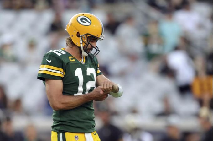 Football-Quarterback Aaron Rodgers erhält über seinen Helm Anweisungen. Auf seinem Arm sind die Namen aller Spielzüge notiert. Rodgers
