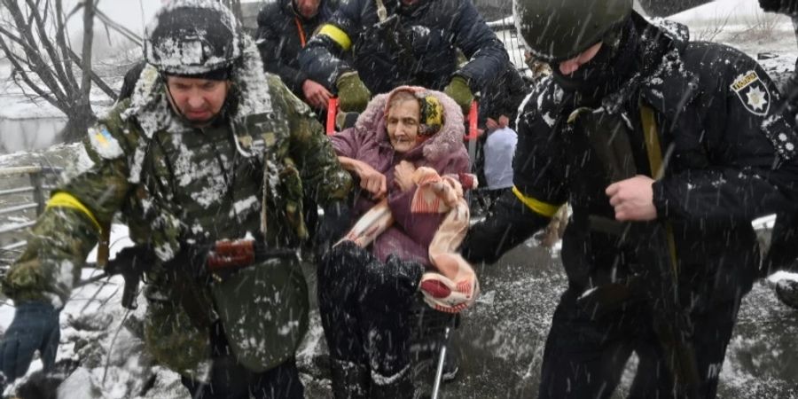 Ukrainische Soldaten helfen Frau über Fluss bei Kiew