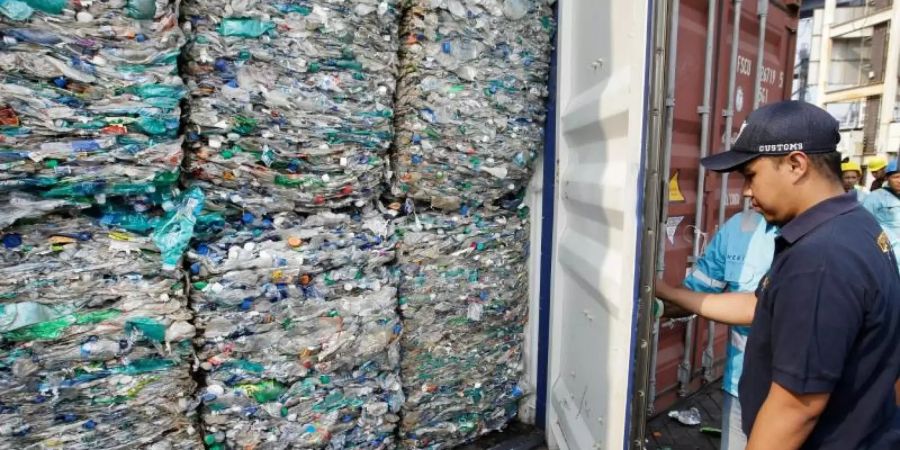 Ein Zollbeamter verschliesst am Hafen von Tanjung Priok einen Container mit Plastikmüll. Foto: Achmad Ibrahim/AP/dpa