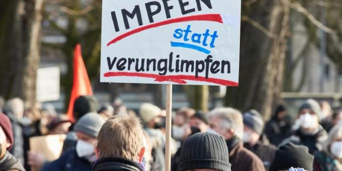 Ein Teilnehmer hält ein Transparent mit der Aufschrift „Impfen statt verunglimpfen!“ auf der Mohrweide am Dammtorbahnhof. Foto: Georg Wendt/dpa Coronavirus