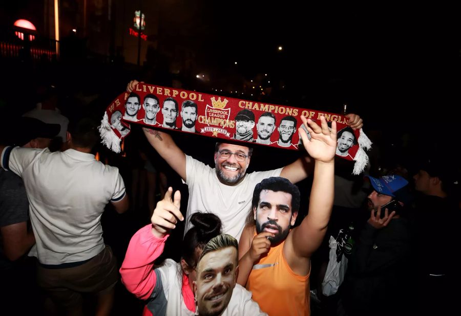 Liverpooler Fans, die Gesichtsmasken von Jordan Henderson (vorne), Mohamed Salah (r.) und Jürgen Klopp tragen, feiern die Meisterschaft.