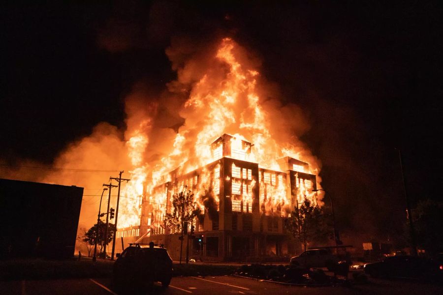 Ein mehrstöckiges Wohngebäude steht in Flammen. Proteste, Plünderungen, Brandstiftungen und Tränengas: Die US-Stadt Minneapolis befindet sich nach dem Tod eines Schwarzen bei einem brutalen Polizeieinsatz in Aufruhr.