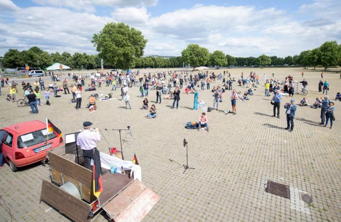 Teilnehmer stehen und sitzen während einer Demonstration gegen die Corona-Massnahmen auf dem Cannstatter Wasen in Stuttgart. corona-demo stuttgart