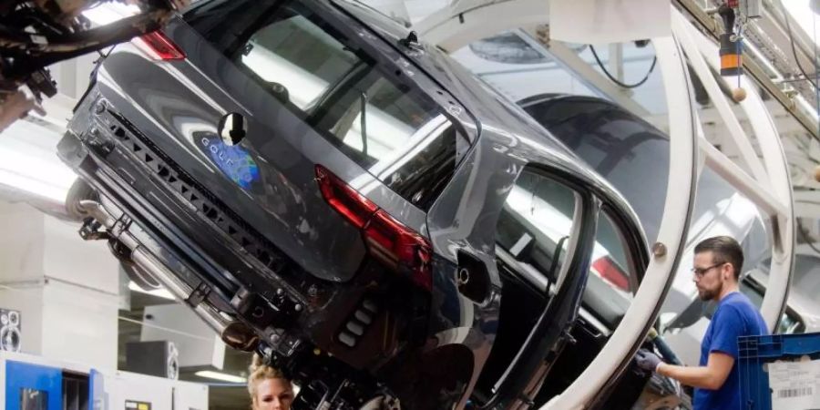Mitarbeiter arbeiten im Hauptwerk in Wolfsburg im Oktober 2019 an einem Golf 8. Foto: Julian Stratenschulte/dpa