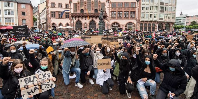 05.06.2020, Hessen, Frankfurt/Main: Auf Knien und mit in die Höhe gestreckter Faust bekunden Demonstranten auf dem Römerberg in Frankfurt ihre Solidarität mit den Anti-Rassismus-Protesten in den USA. Insgesamt waren zu der «Black-Lives-Matter» Kundgebung knapp zehntausend Menschen gekommen. Foto: Boris Roessler/dpa +++ dpa-Bildfunk +++ Nach dem Tod von George Floyd - Frankfurt