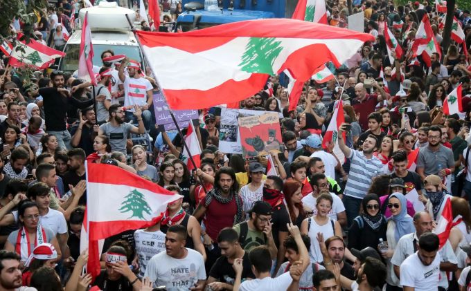 Demonstranten schwenken während eines Protestes gegen die Regierung libanesische Flaggen. Proteste im Libanon
