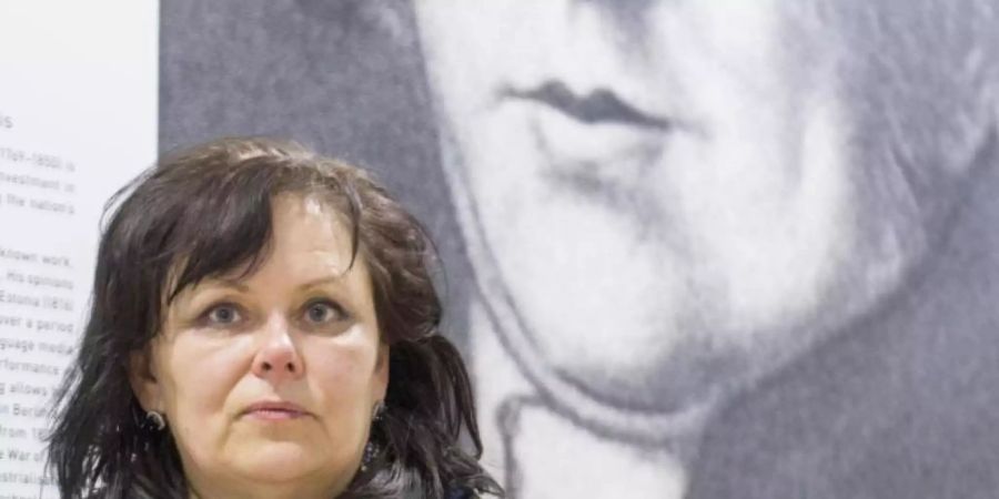 Kuratorin Aija Taimina steht in der Nationalbibliothek am Eingang zur Ausstellung vor einem Poster mit einem Porträt des Publizisten Garlieb Merkel (1769-1850). Foto: Alexander Welscher/dpa