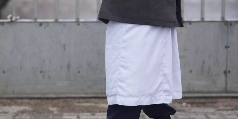Ein Mann in traditioneller Bekleidung steht vor einem Versammlungsort von Salafisten. Foto: Florian Schuh/dpa